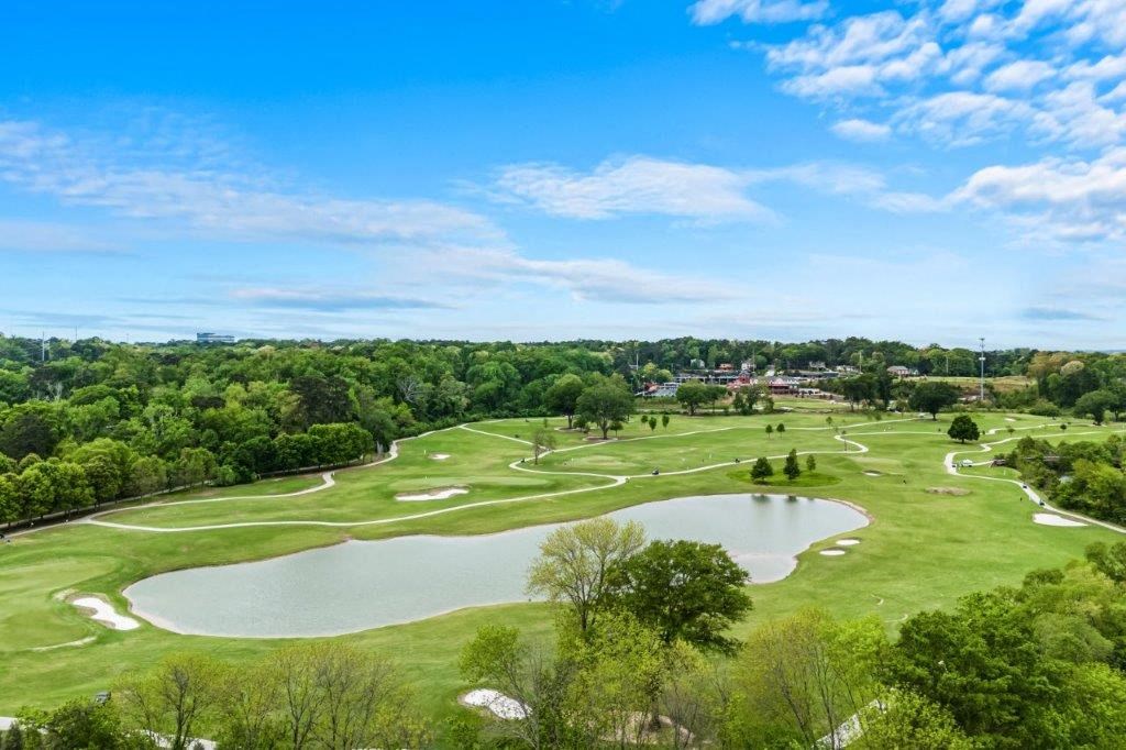 an aerial view of a golf course with a pond and trees
