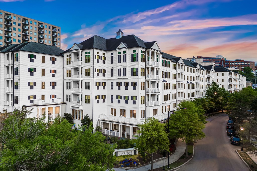 a large white building with trees and a street in front of it