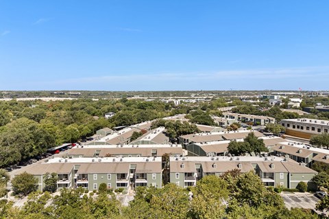 A bird's eye view of a residential area with multiple houses and a clear blue sky.