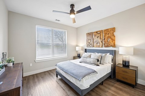 A bedroom with a bed, nightstand, and a ceiling fan.