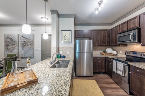 A kitchen with a granite counter top and stainless steel appliances.