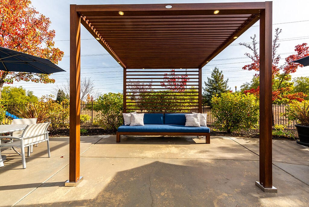a blue couch sitting under a wooden pergola on a patio