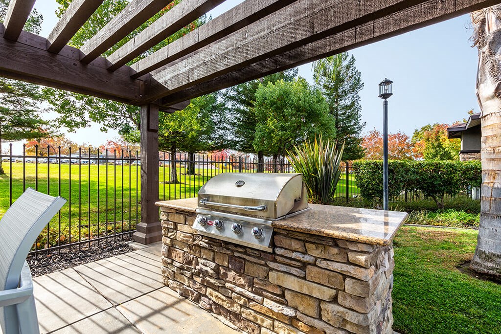 an outdoor kitchen with a grill on a stone wall