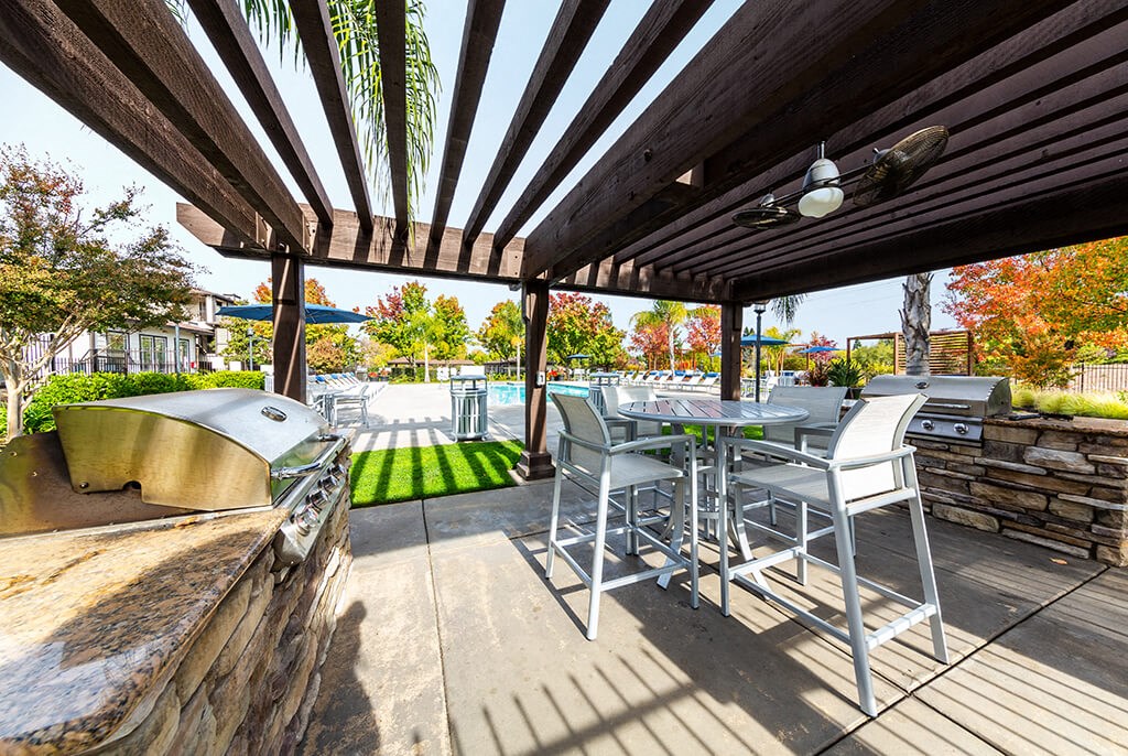 the outdoor patio has a grill and tables with chairs