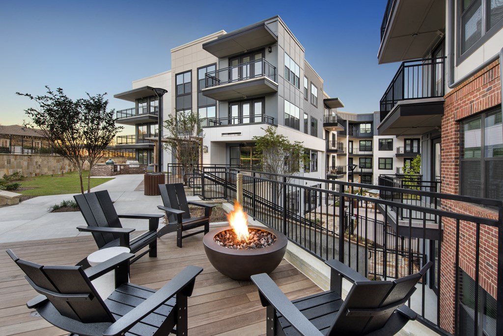 an outdoor patio with a fire pit and chairs