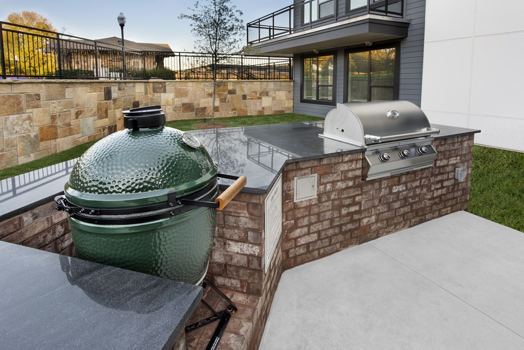 the outdoor kitchen has a grill and a table on the patio