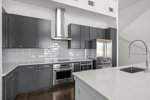 A modern kitchen with dark grey cabinets and stainless steel appliances.