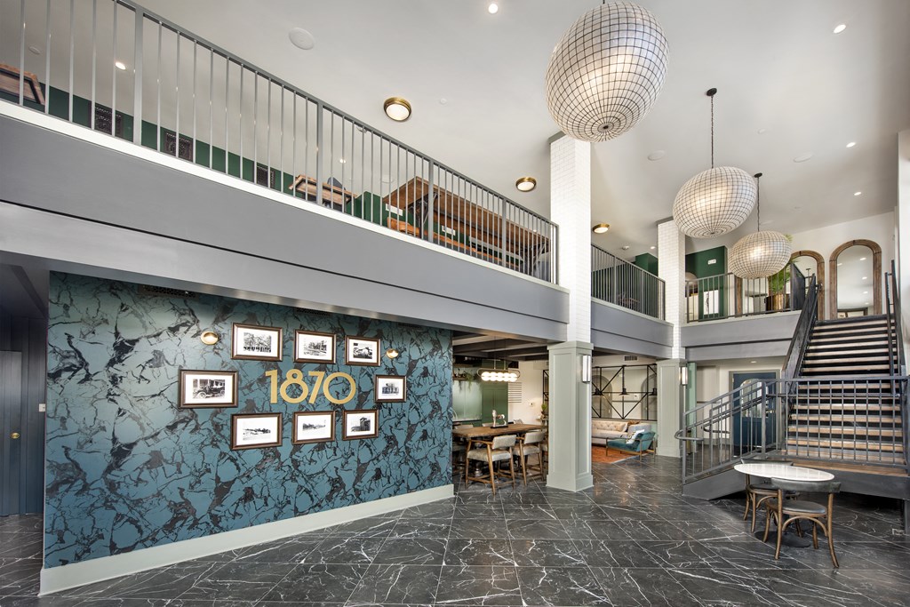 a lobby with a staircase and a green wall with pictures on it