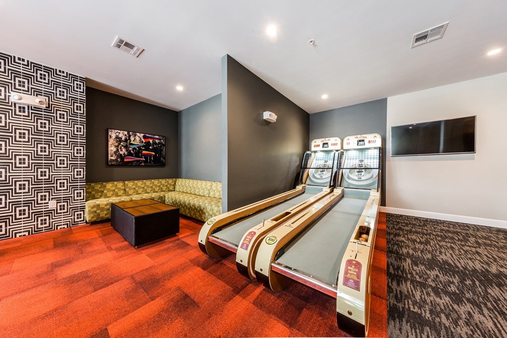 a game room with four shuffleboards and a tv