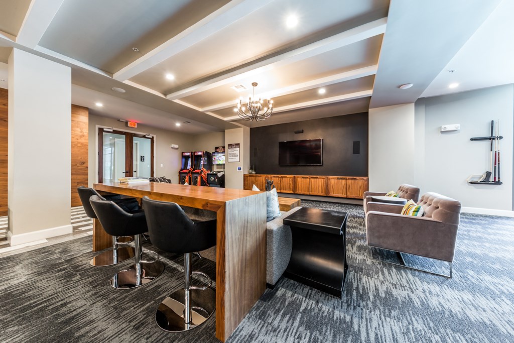 a lounge area with a bar and chairs and a tv
