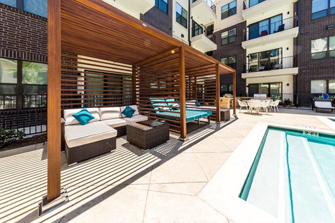 a patio with a pool and a wooden canopy