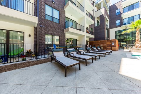 an outdoor patio with lounge chairs and a pool at an apartment building