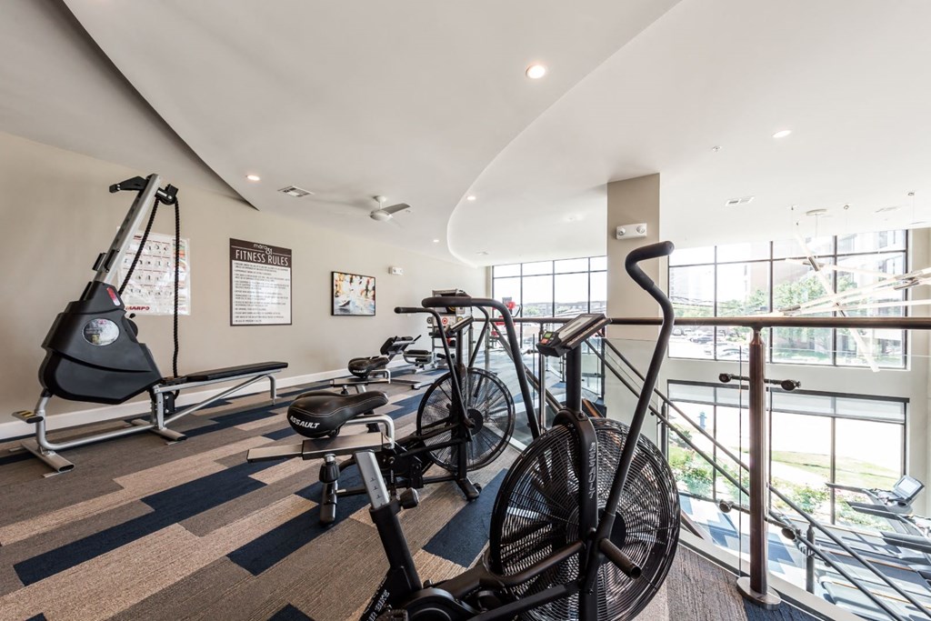 a gym with bikes and weights in a room with windows