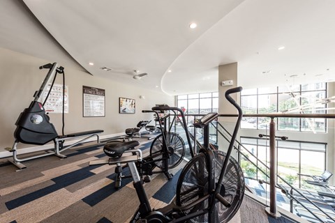 a gym with bikes and weights in a room with windows