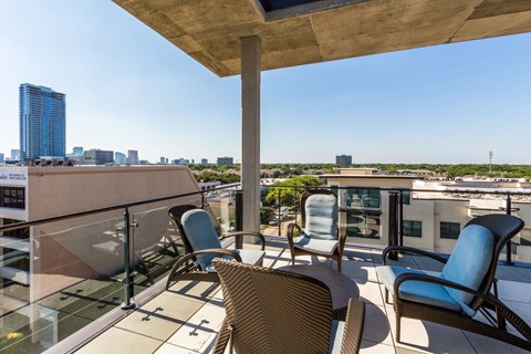a balcony with patio furniture and a city in the background