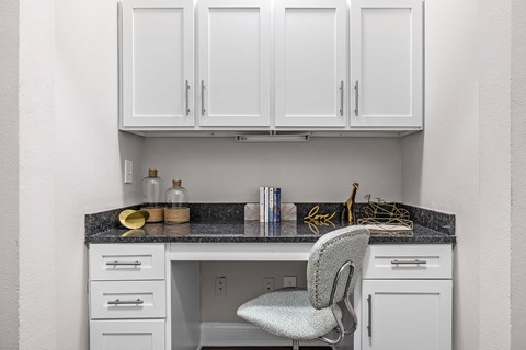 A kitchen with white cabinets and a grey chair.