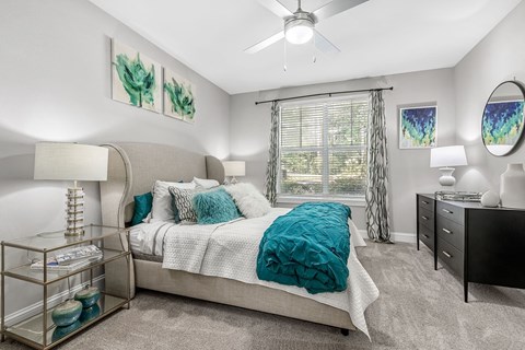 A bedroom with a bed, nightstand, and a ceiling fan.