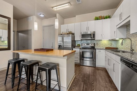 A kitchen with white cabinets and a wooden island.