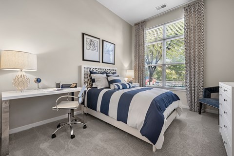 a bedroom with a bed and a desk with a window