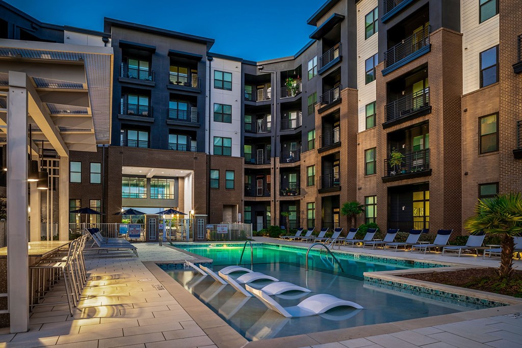 a swimming pool in front of an apartment building at night