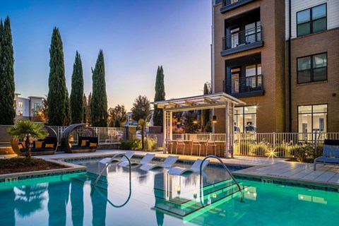 apartments with a swimming pool and a gazebo at dusk