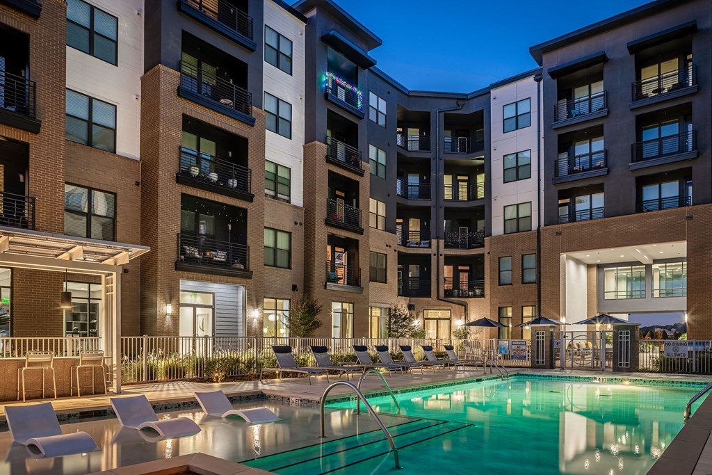 a swimming pool in front of a large apartment building at night