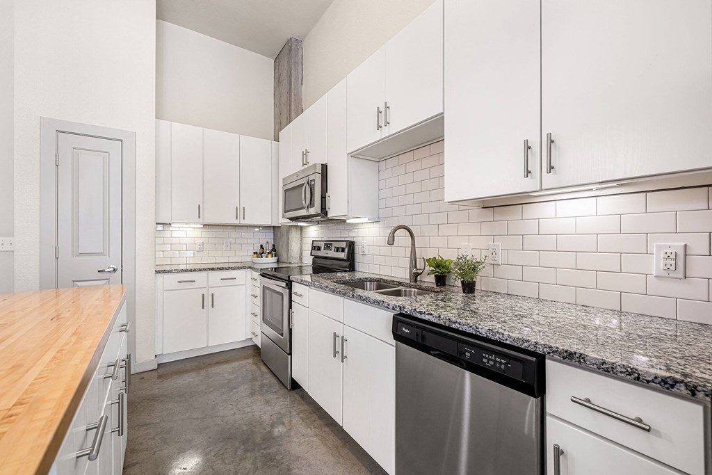 a kitchen with white cabinets and granite counter tops