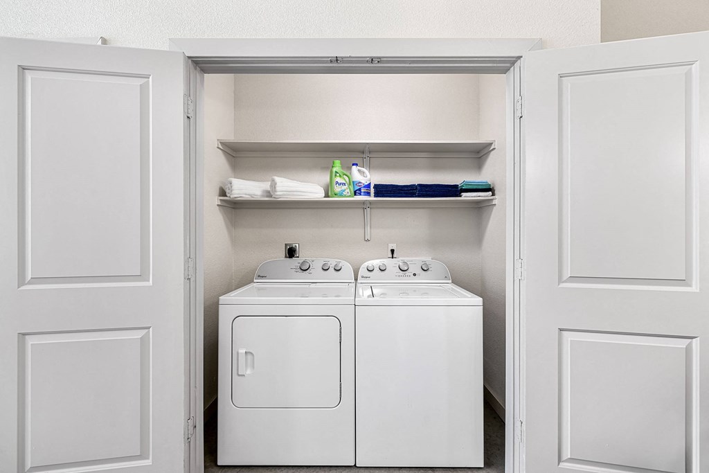 a white washer and dryer in a laundry room with white cabinets