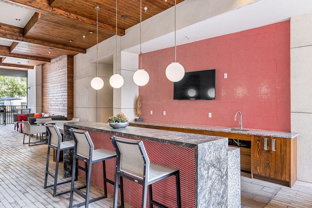 a kitchen with a long counter and chairs in front of a dining room
