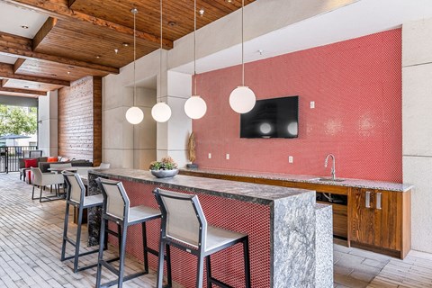 a kitchen with a long counter and chairs in front of a dining room