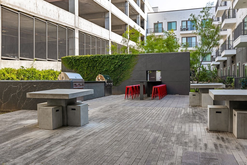 a courtyard with benches and red chairs in front of a building
