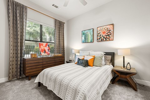 A bedroom with a large bed and a window with curtains.