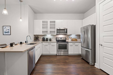 A modern kitchen with white cabinets and stainless steel appliances.