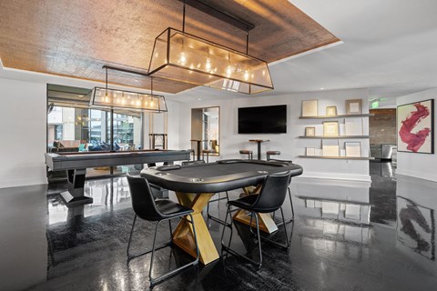 a black table with chairs in a room with a pool table and a television