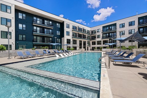 A large swimming pool in front of apartment buildings.
