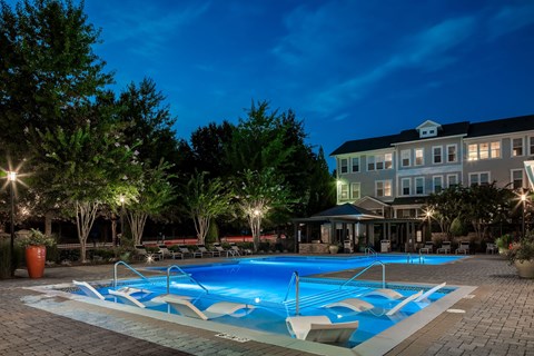 A swimming pool surrounded by trees and lights at night.