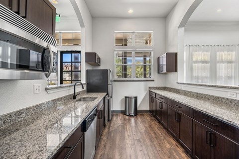 A modern kitchen with dark wood cabinets and granite countertops.