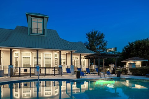 a swimming pool with chairs and a building in the background