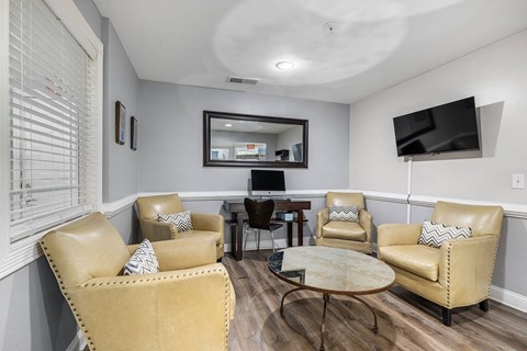 A living room with tan leather chairs and a round coffee table.