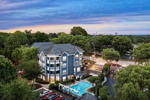 A large apartment complex with a pool and cars parked in the driveway.