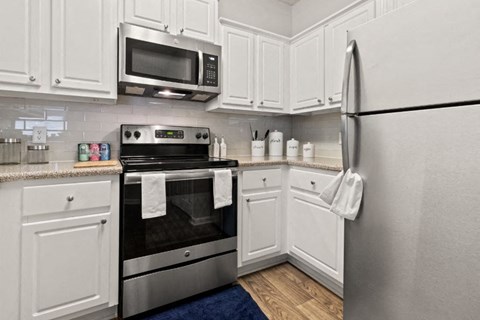 A kitchen with white cabinets and a stainless steel refrigerator.