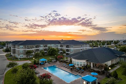 A sunset view of a resort with a pool and multiple buildings.