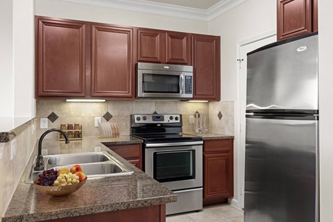 A kitchen with brown cabinets and a stainless steel refrigerator.