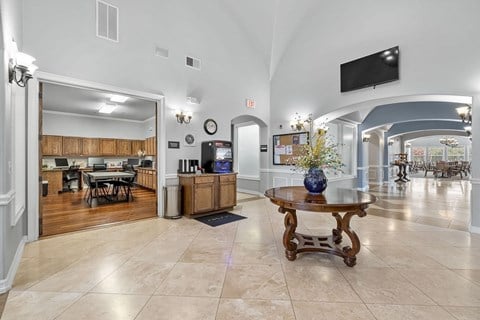 A spacious living room with a television mounted on the wall and a wooden coffee table in the center.