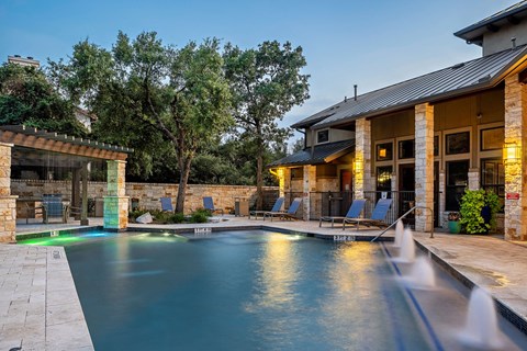 A pool with a waterfall in front of a house.