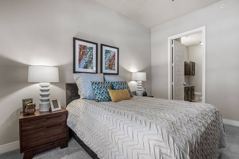A bedroom with a bed, nightstand, and two wall lamps.