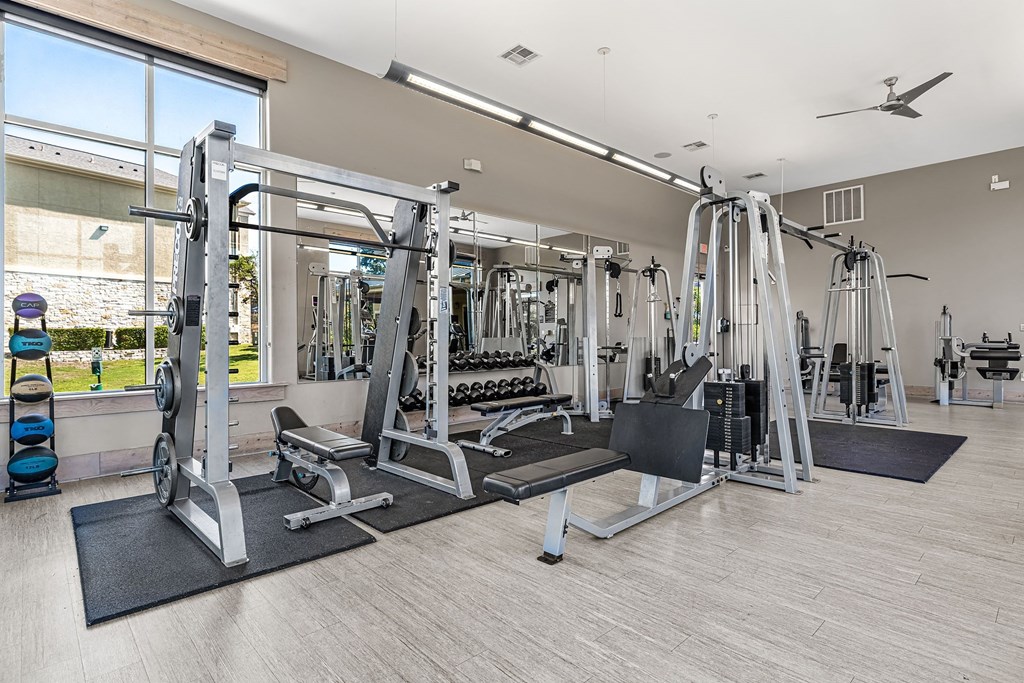 a gym with weights and cardio equipment and a large window