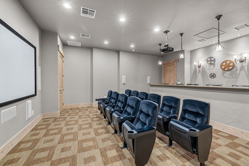 a theater room with a row of blue chairs and a projection screen