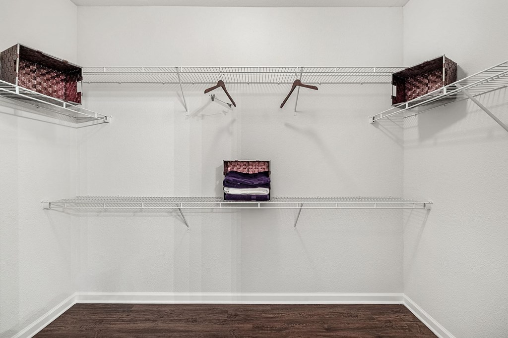 a walk in closet with white walls and shelves and hanging racks