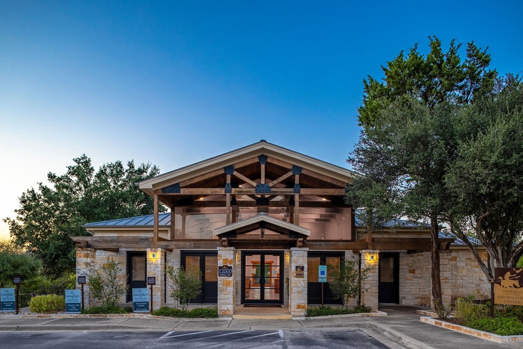 the front entrance of a hotel with trees and a blue sky
